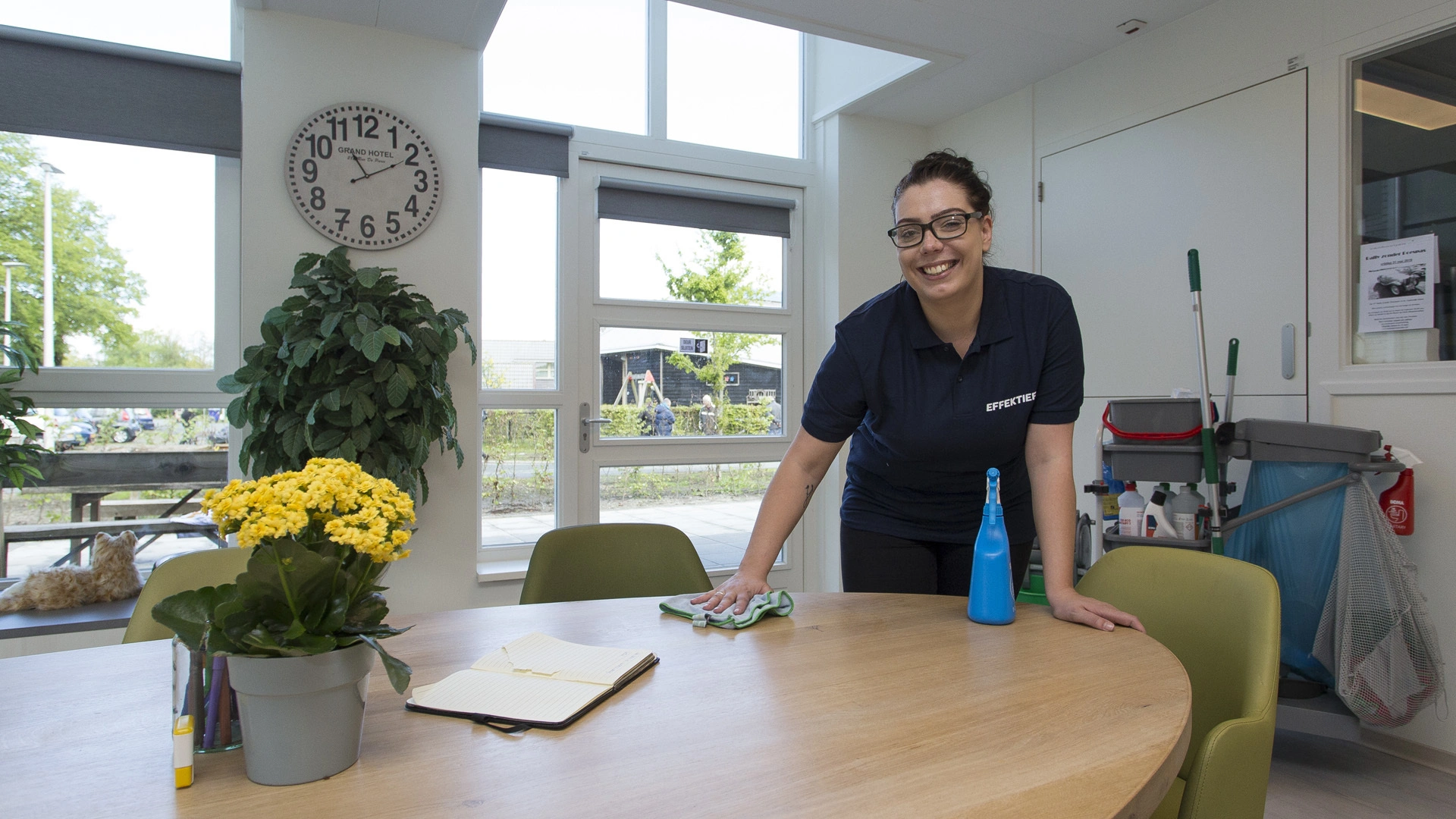 Schoonmaakmedewerker poetst een tafel tijdens professionele schoonmaak